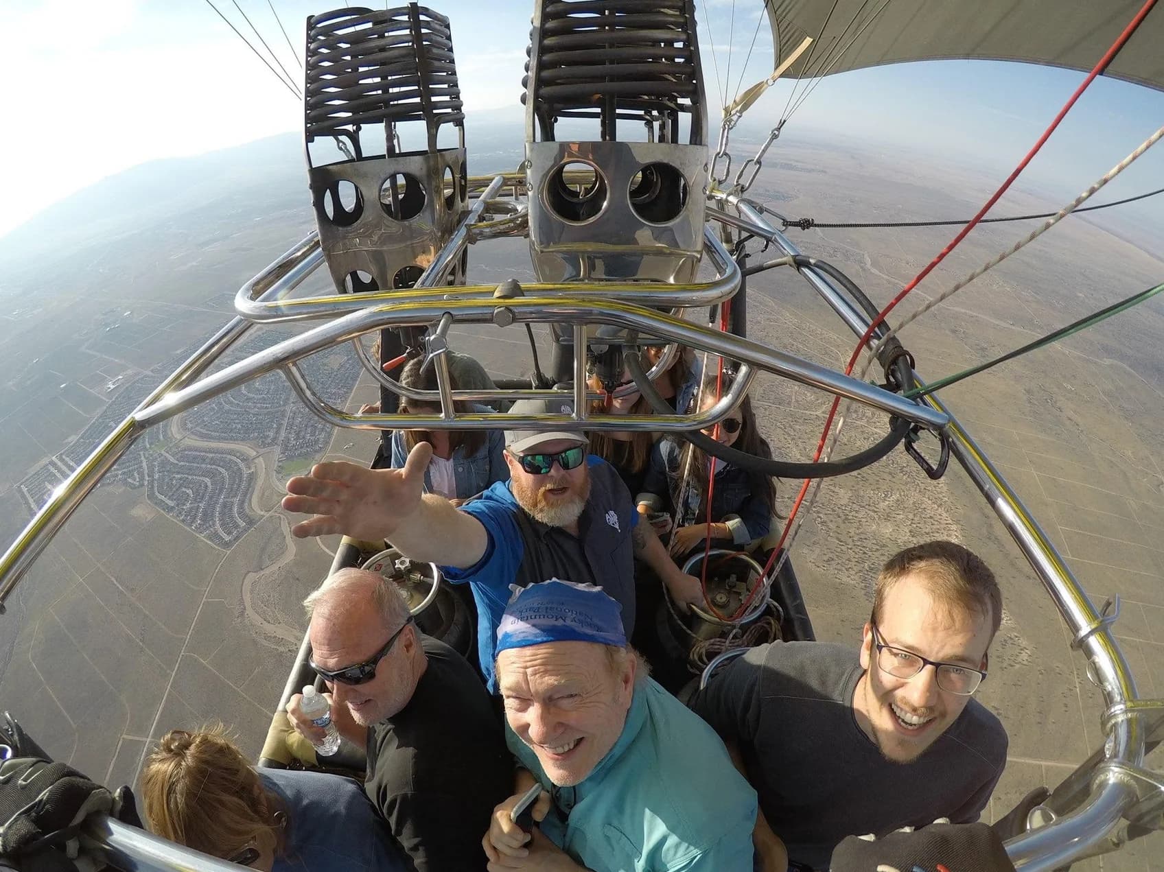 Pilot and passengers smiling in a hot-air balloon basket beneath the burners