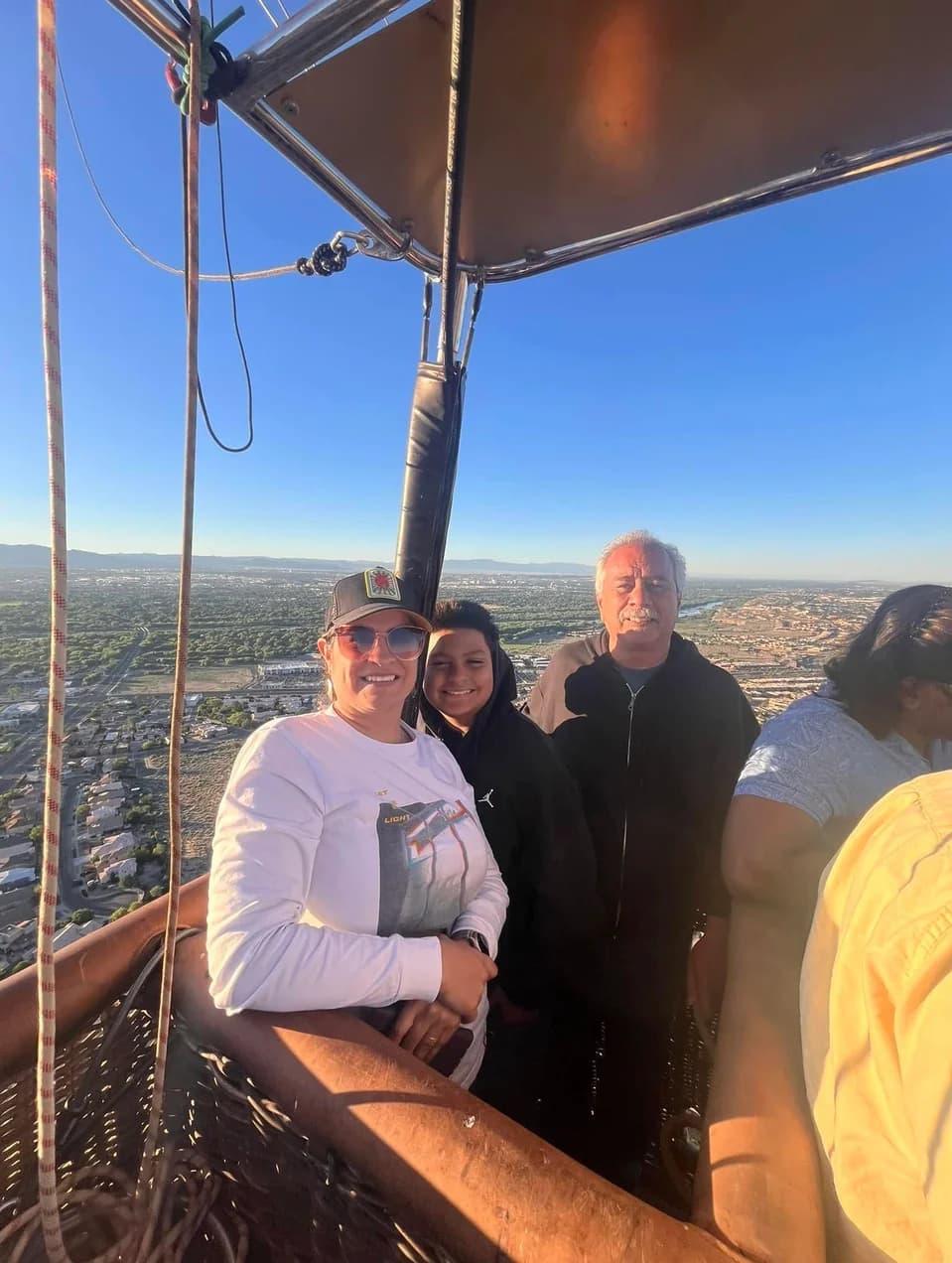 Passengers standing in a hot-air balloon basket with the landscape behind them
