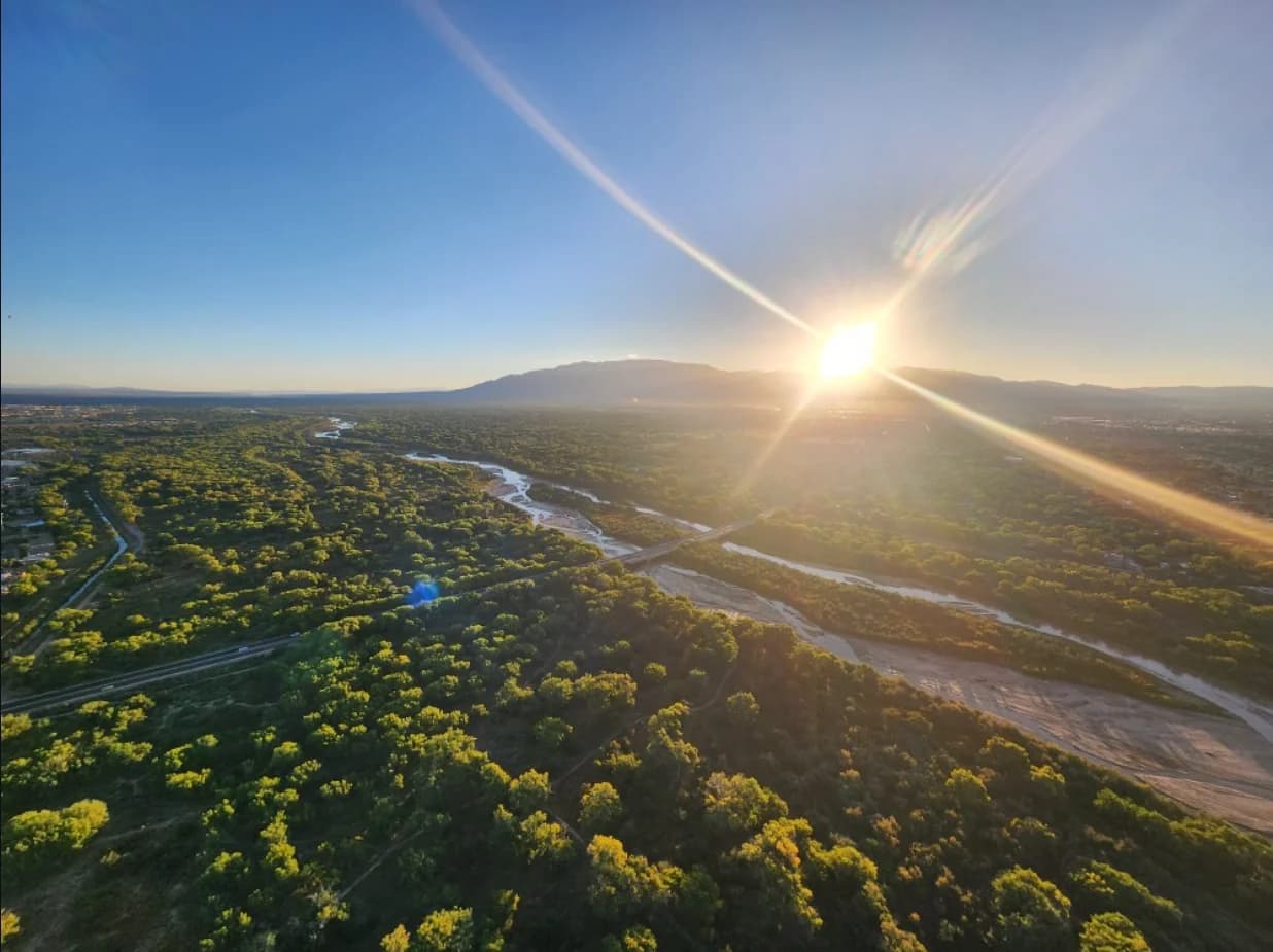 Sun rising over the mountains and tree-lined Rio Grande valley in Albuquerque