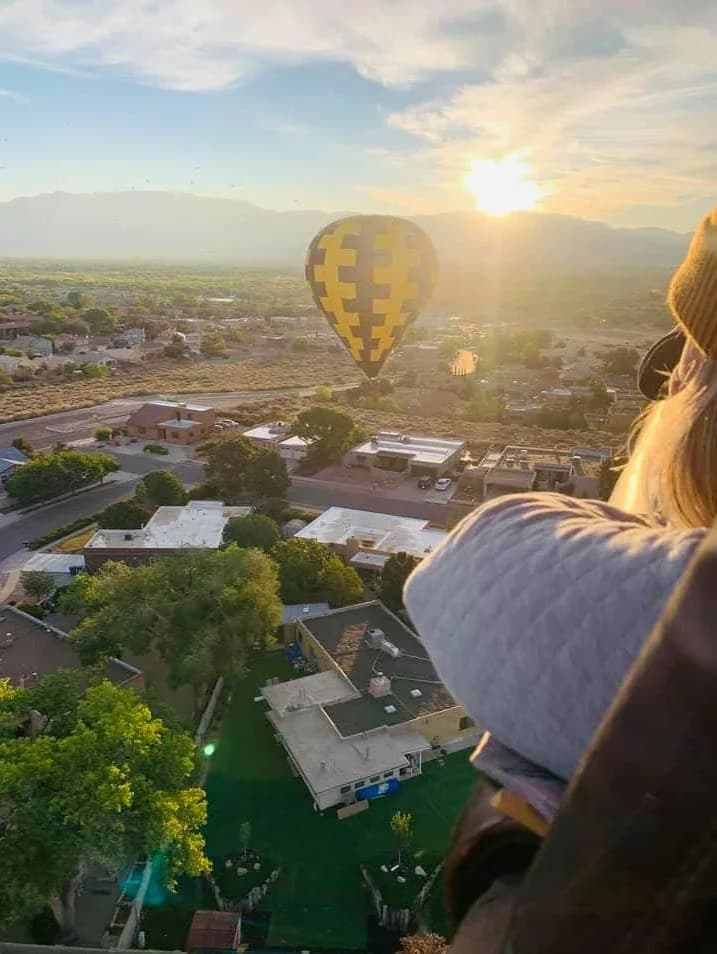 View from a balloon basket toward other hot-air balloons at sunrise